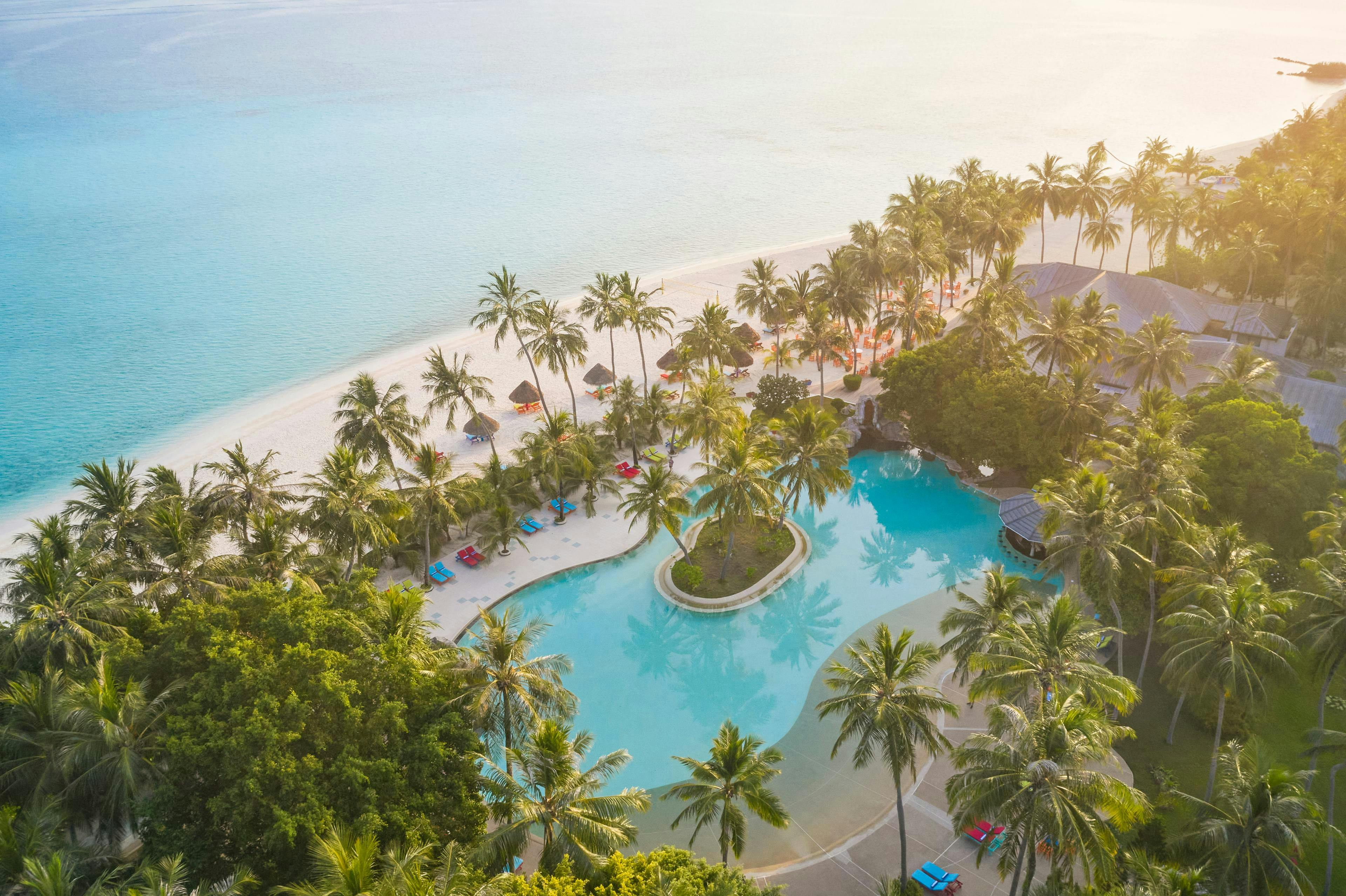 Poollandschaft zwischen Palmen und Strand