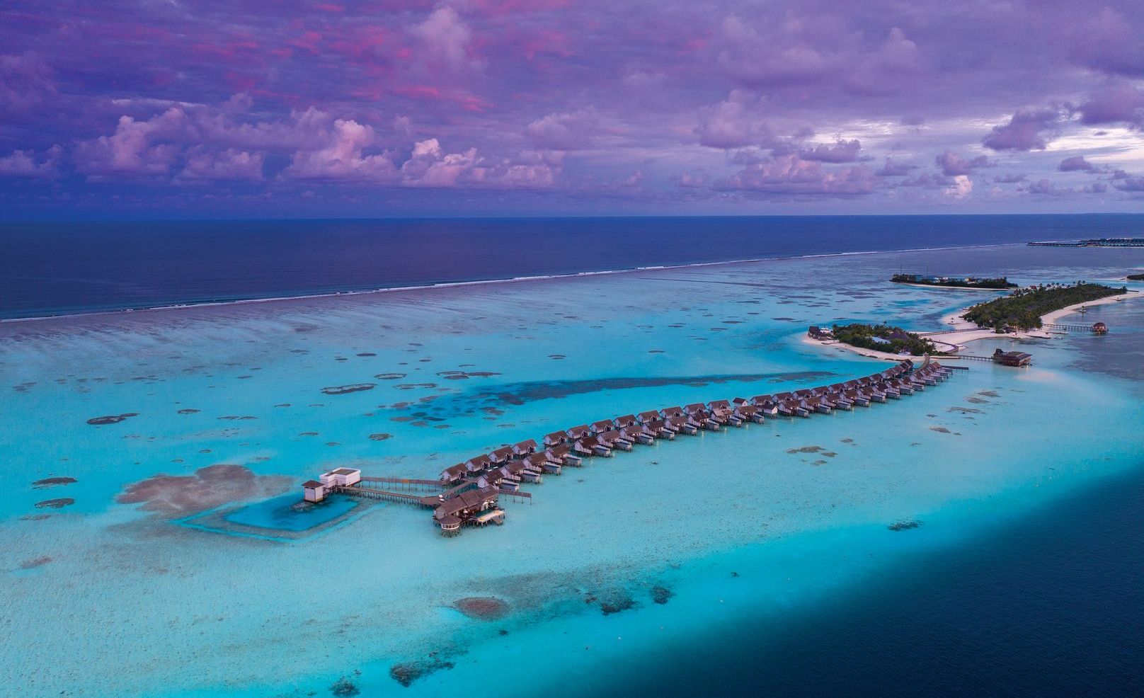 Luftaufnahme von OZEN Life Maadhoo mit der gesamten Insel, weißen Stränden, türkisfarbener Lagune und mehreren Wasservillen im Süd-Malé-Atoll